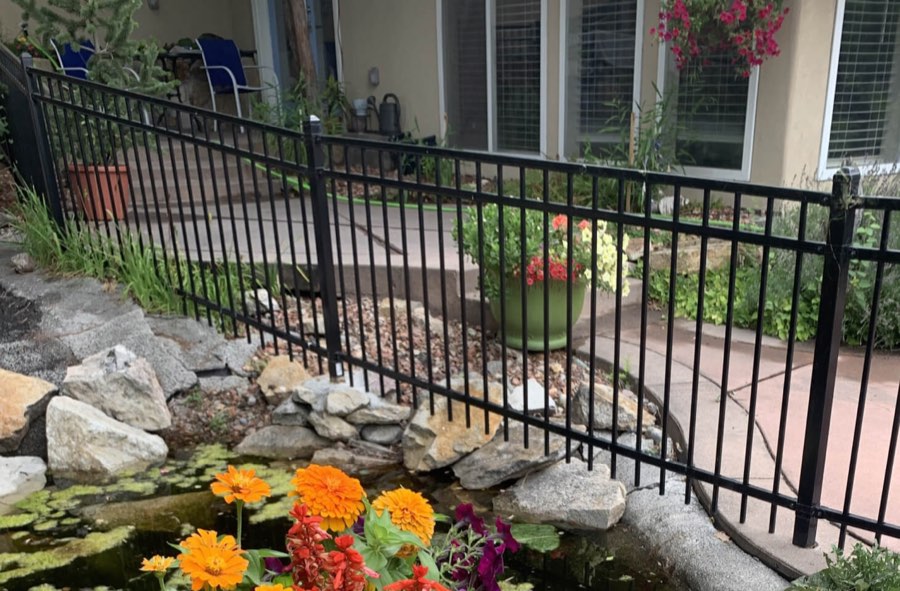 Wrought iron fence around a Spokane backyard with a garden pond, built by Neighborhood Fence